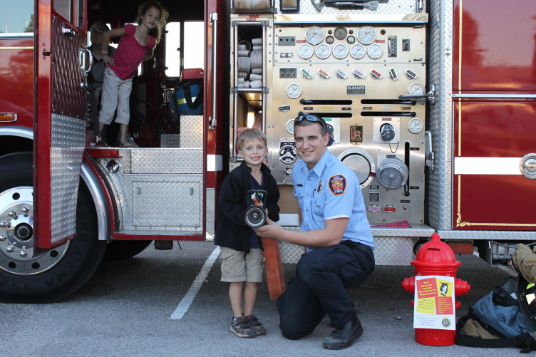 A firefighter with children beside a red fire engine