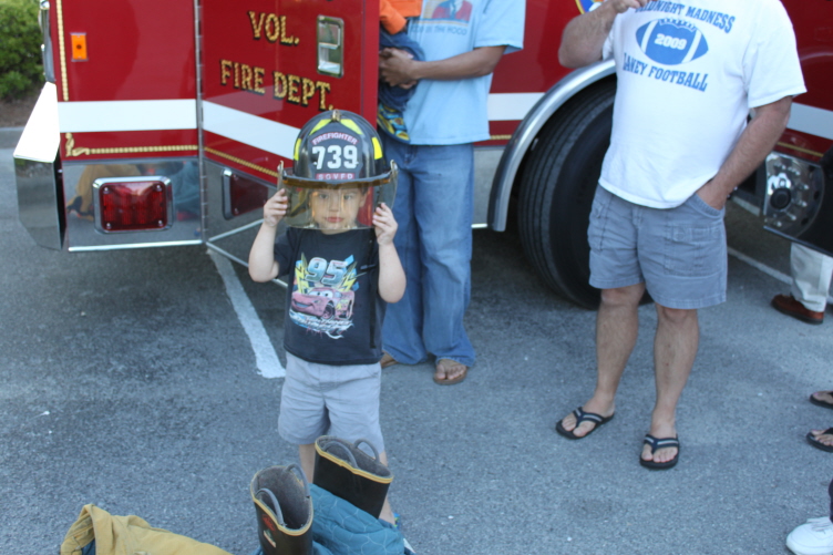 A young boy wearing an oversized firefighter helmet